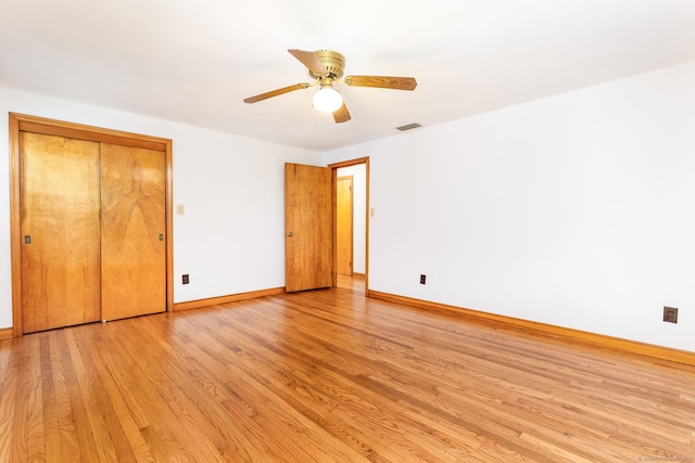 unfurnished bedroom with a closet, light wood-style flooring, baseboards, ceiling fan, and visible vents