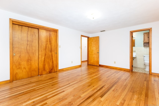 unfurnished bedroom featuring connected bathroom, a closet, visible vents, baseboards, and light wood-style floors
