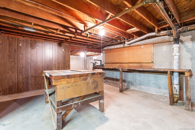 unfinished below grade area with a workshop area and wooden walls