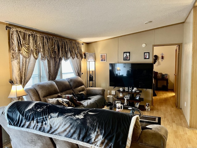 living area with a textured ceiling, wood finished floors, lofted ceiling, and ornamental molding