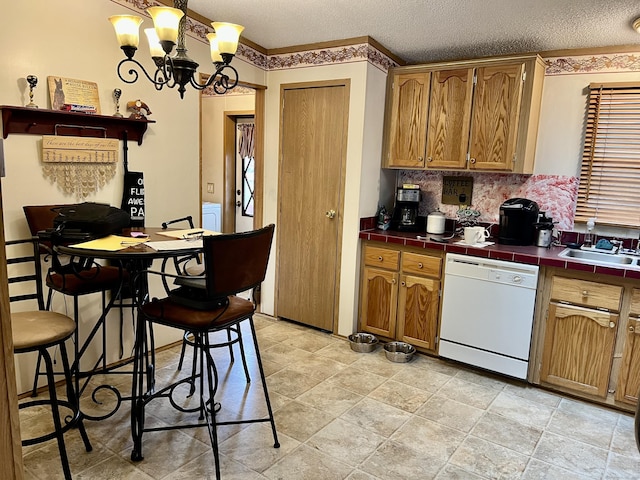 kitchen featuring a sink, a textured ceiling, dishwasher, decorative backsplash, and tile counters