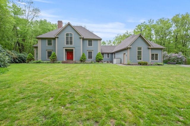 colonial inspired home featuring a chimney and a front yard