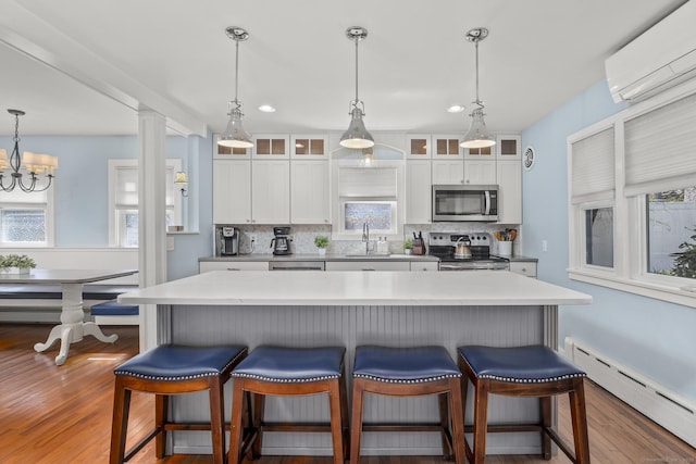 29 Old Neversink Rd, Danbury, CT 06811 - kitchen with decorative backsplash, a kitchen bar, baseboard heating, a wall mounted AC, and stainless steel appliances