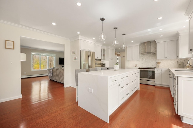 kitchen featuring appliances with stainless steel finishes, a sink, wall chimney exhaust hood, a center island, and a baseboard heating unit