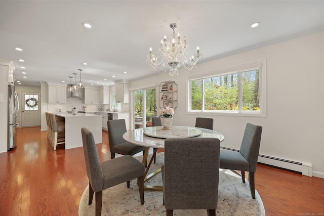 dining space with a baseboard radiator, ornamental molding, recessed lighting, and a chandelier