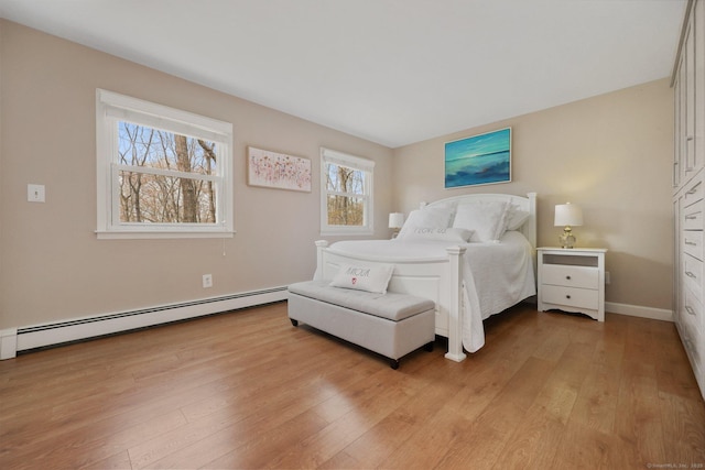 bedroom with baseboards, a baseboard radiator, and light wood-style flooring