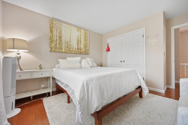 bedroom with a closet, baseboards, and wood finished floors