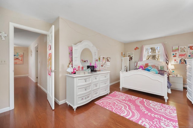 bedroom featuring baseboard heating, baseboards, and wood finished floors
