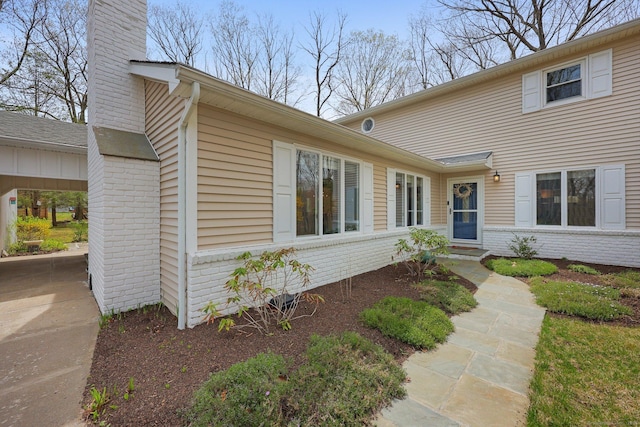view of front of house with brick siding, a chimney, and entry steps