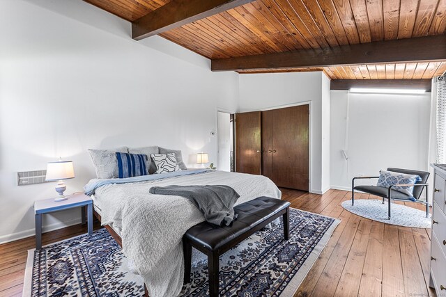 bedroom featuring wood-type flooring, baseboards, beamed ceiling, wood ceiling, and a closet