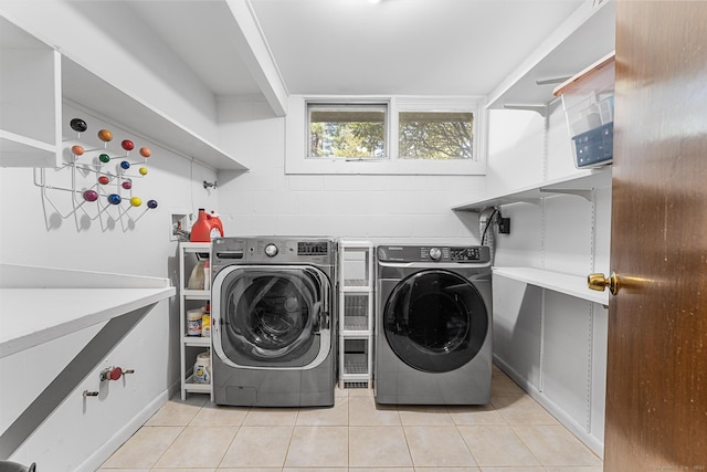 clothes washing area with laundry area, washing machine and dryer, and light tile patterned floors