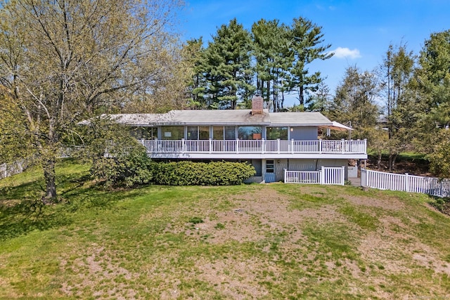 back of house featuring a lawn, fence, a chimney, and a deck