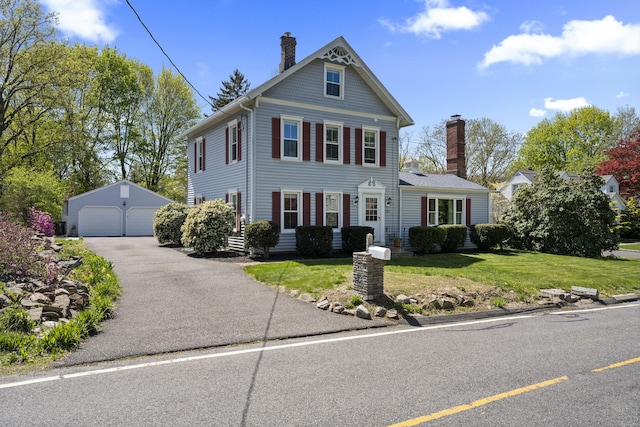 view of front of property featuring a garage, an outbuilding, a chimney, and a front lawn