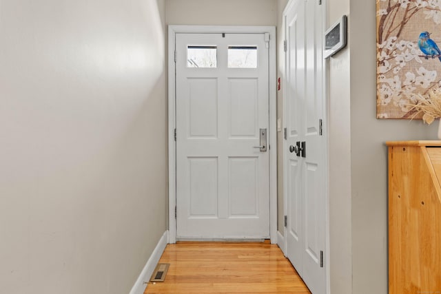 doorway with visible vents, light wood-style flooring, and baseboards