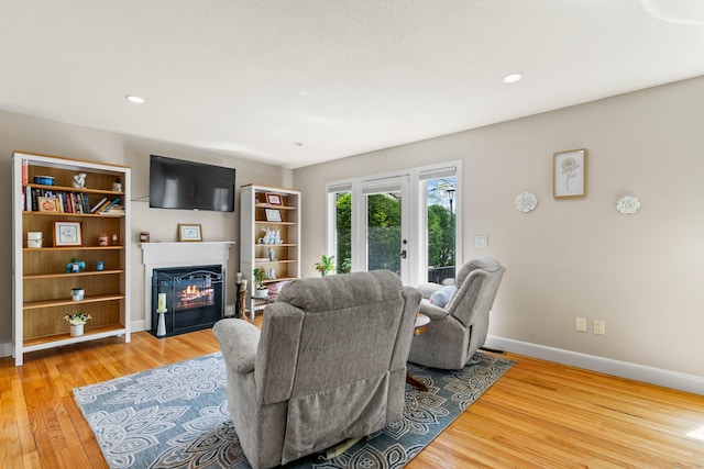 living room with a glass covered fireplace, baseboards, light wood-style floors, and recessed lighting