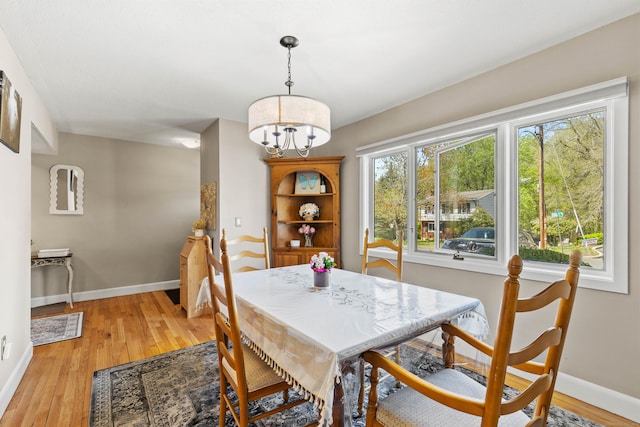 dining area featuring baseboards, an inviting chandelier, and light wood-type flooring