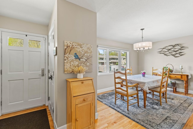 dining area with an inviting chandelier, baseboards, and light wood-type flooring