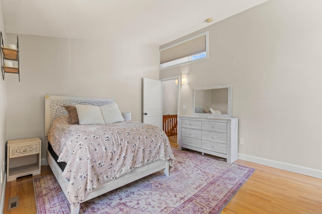 bedroom with baseboards, visible vents, and wood finished floors