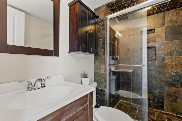 bathroom featuring toilet, a shower stall, and vanity