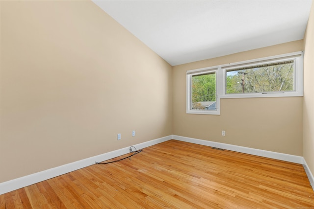 unfurnished room featuring baseboards, vaulted ceiling, and light wood-style flooring