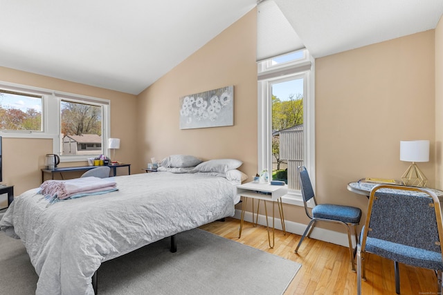 bedroom featuring multiple windows, cooling unit, vaulted ceiling, and wood finished floors