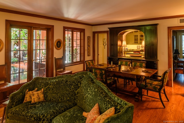 dining space with ornamental molding, a healthy amount of sunlight, and wood finished floors
