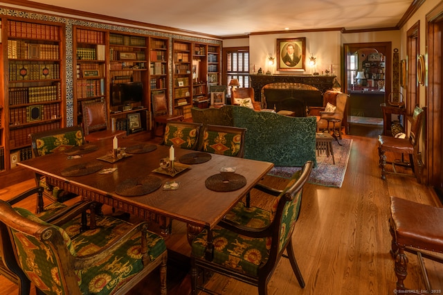 dining space with a fireplace, crown molding, and wood finished floors