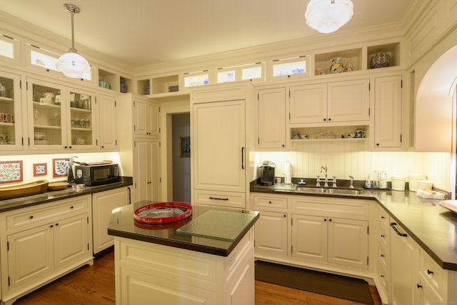 kitchen featuring arched walkways, dark countertops, open shelves, and a sink