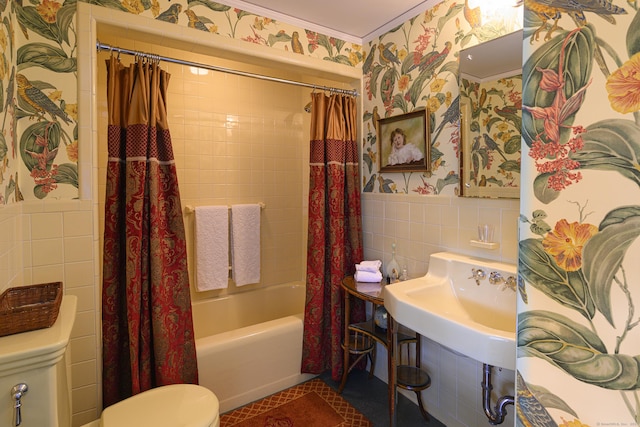 bathroom featuring toilet, tile walls, a wainscoted wall, shower / bath combo, and wallpapered walls