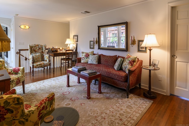 living room with baseboards, ornamental molding, visible vents, and wood finished floors