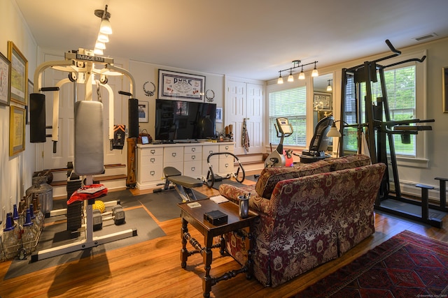 living room featuring a wealth of natural light, visible vents, wood finished floors, and a baseboard radiator