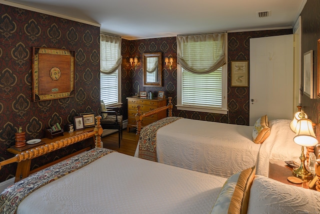 bedroom with wallpapered walls, visible vents, wood finished floors, and ornamental molding