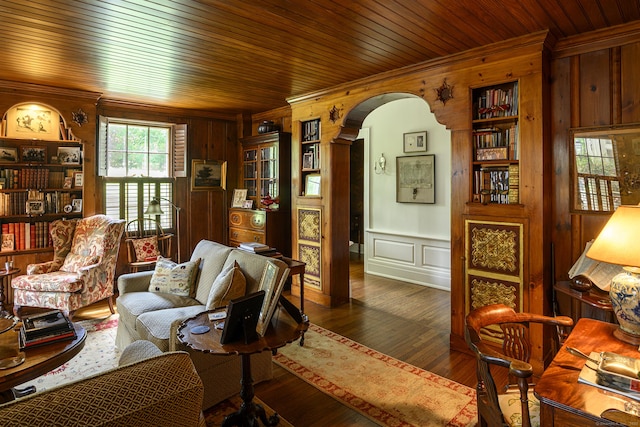 living area featuring a decorative wall, ornamental molding, arched walkways, and wood walls