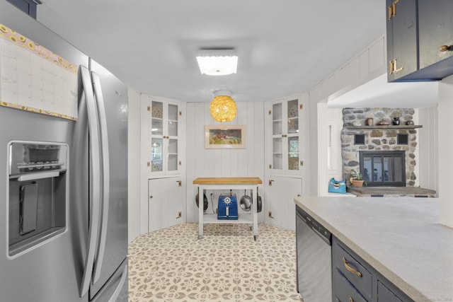 kitchen with light countertops, appliances with stainless steel finishes, and a stone fireplace