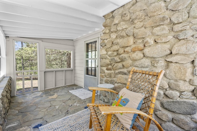 sunroom with stone flooring and beamed ceiling
