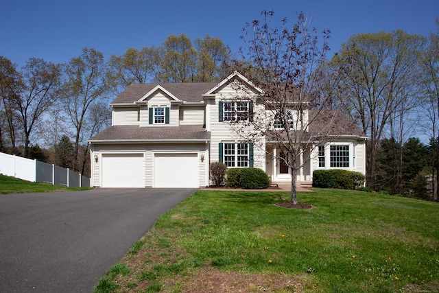 traditional-style house with an attached garage, fence, driveway, and a front yard
