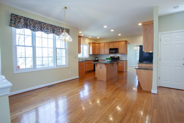 kitchen with dark countertops, black microwave, range, a kitchen island, and visible vents