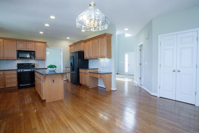 kitchen with backsplash, an inviting chandelier, black appliances, and hardwood / wood-style floors