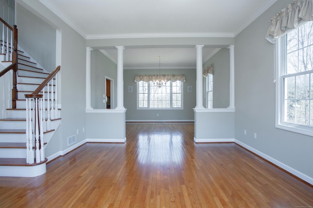 interior space with visible vents, stairs, wood finished floors, baseboards, and ornate columns