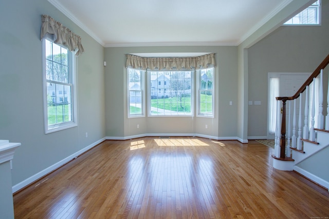 unfurnished living room featuring stairway, baseboards, ornamental molding, and hardwood / wood-style floors