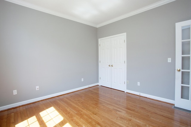 unfurnished bedroom with light wood-style floors, baseboards, ornamental molding, and a closet