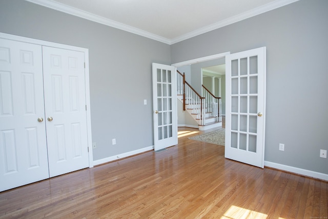 spare room with crown molding, french doors, stairs, baseboards, and light wood-type flooring