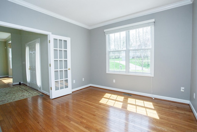 spare room with baseboards, visible vents, ornamental molding, and hardwood / wood-style flooring