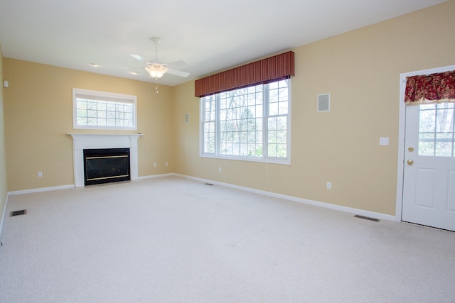 unfurnished living room with ceiling fan, visible vents, and a wealth of natural light
