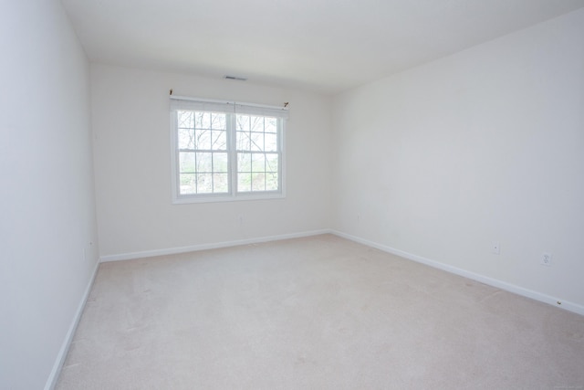 spare room with visible vents, baseboards, and light carpet