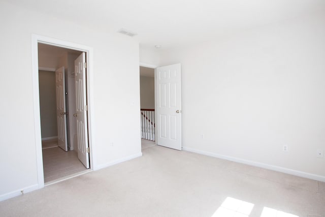 unfurnished bedroom with carpet floors, baseboards, and visible vents