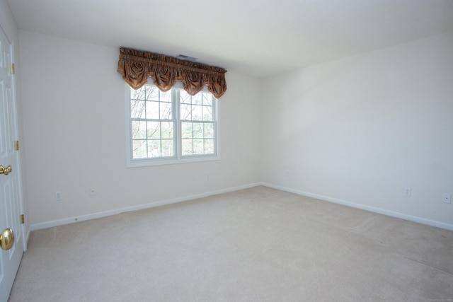 unfurnished room with baseboards and light colored carpet