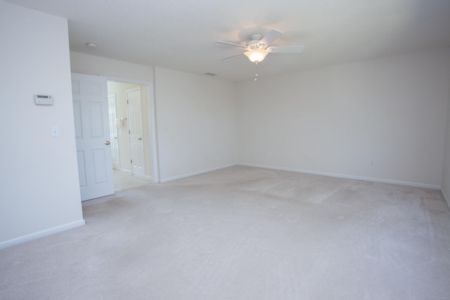 spare room featuring baseboards, light carpet, and a ceiling fan
