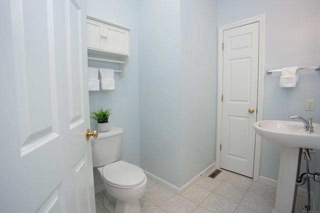 half bath with baseboards, tile patterned floors, and toilet