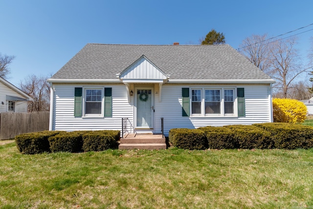 bungalow-style home with fence, roof with shingles, and a front lawn
